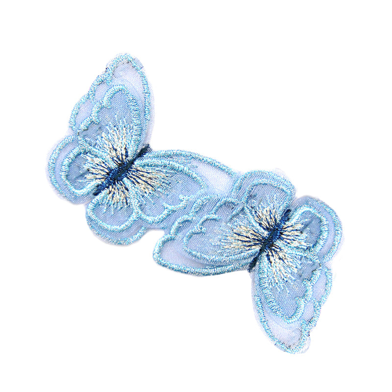 A pair of blue embroidered butterfly appliques on a white background.