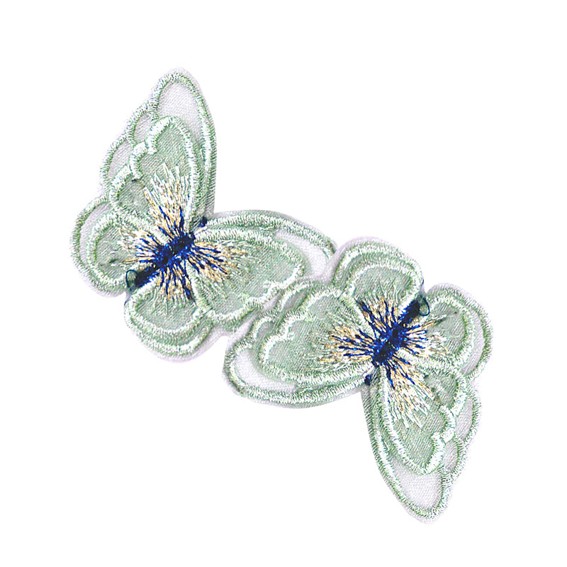 Two green embroidered butterfly appliques with blue and yellow details on a white background.