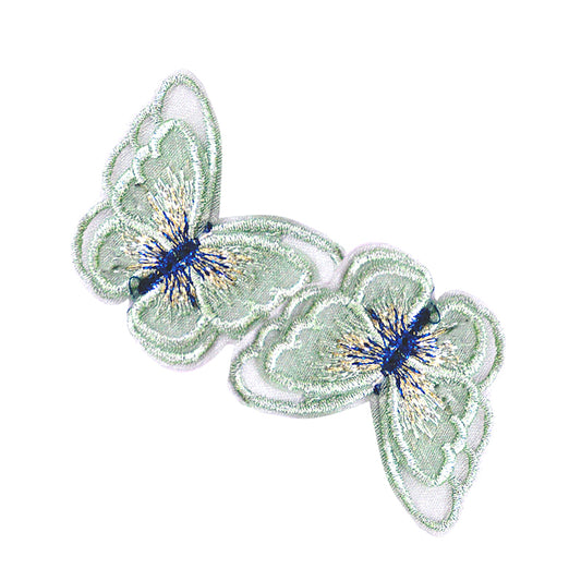 Two green embroidered butterfly appliques with blue and yellow details on a white background.