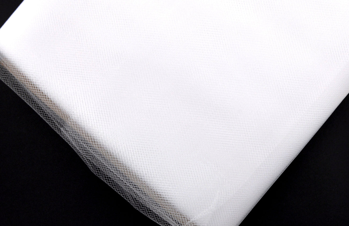 A bolt of white tulle fabric, 54 inches wide, on a plain background.